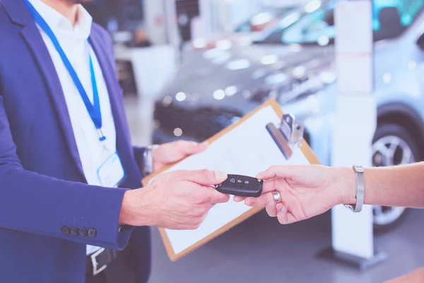 자동차 판매원은 자동차 대리점에서 행복 한 고객에게 자동차를 판매하고 차대 위에 손을 얹는다 — 스톡 사진