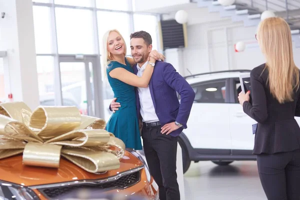 Un hombre hace un regalo un coche a su esposa. Ella está sorprendida de esto. Están muy contentos con esto. — Foto de Stock