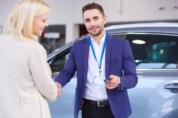 汽车经销商握手与汽车中心快乐女性的形象 — 图库照片