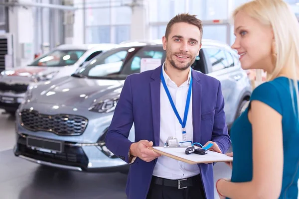 Vendedor de carro vende um carro ao cliente feliz na concessionária de carro e entrega as chaves — Fotografia de Stock