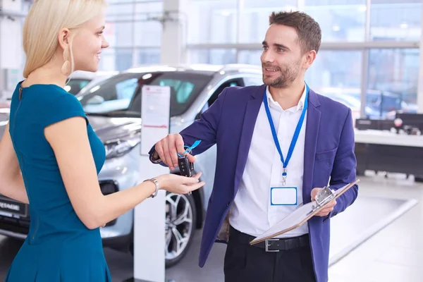 汽车推销员在汽车经销店里把汽车卖给快乐的顾客，然后把钥匙交给顾客 — 图库照片