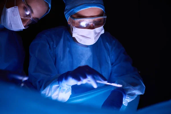 Imagen recortada del bisturí tomada médicos que realizan la cirugía. — Foto de Stock