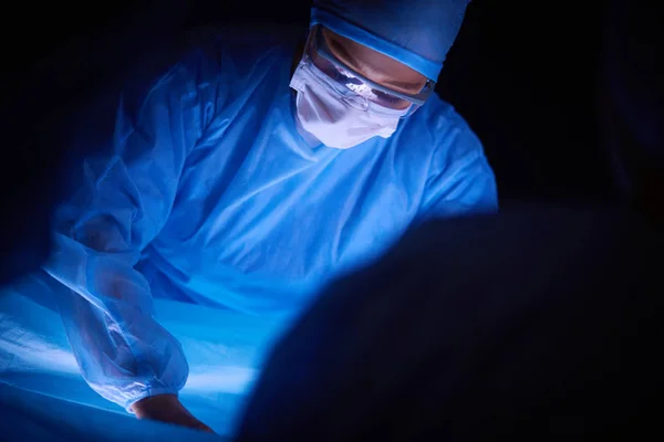 Equipo de médicos en cirugía en un fondo oscuro. — Foto de Stock