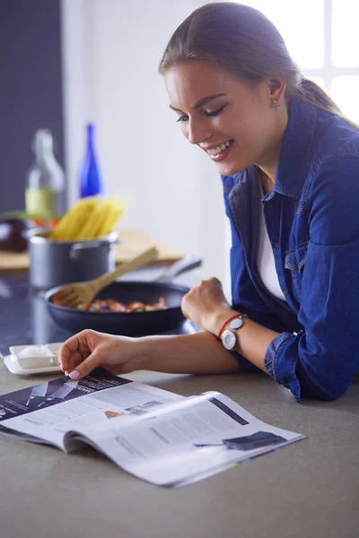 Jonge vrouw eten van ontbijt en tijdschrift lezen — Stockfoto