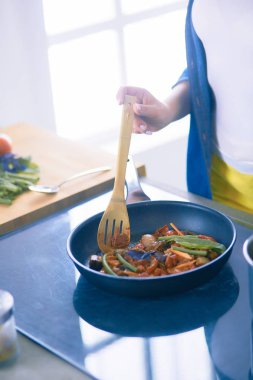 Mutfakta yemek hazırlayan genç bir kadın.