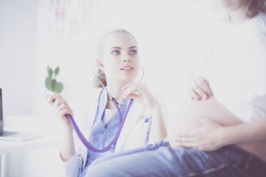 Steteskoplu genç bayan doktor hastanede hamile bir kadınla konuşuyor..