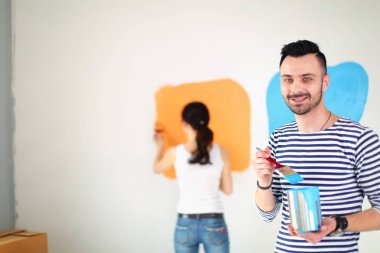 Yeni evin içini boyayan mutlu, genç bir çiftin portresi. Genç çift