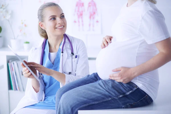 Il medico sorridente mostra le immagini sulla compressa a una giovane donna incinta in ospedale. — Foto Stock