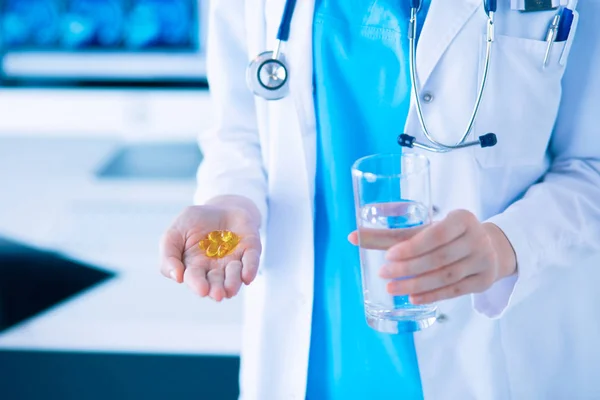 Snímek rukou lékařů držících pilulky a sklenici vody na klinice. — Stock fotografie