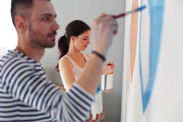 Portrait of happy smiling young couple painting interior wall of new house. young couple — Stock Photo, Image