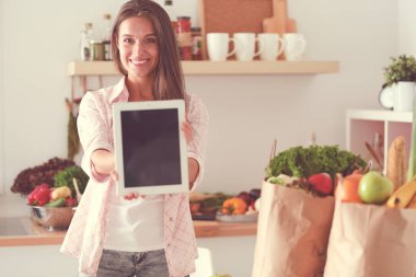 Mutfakta ipad 'ini kullanan genç bir kadın. Genç kadın.