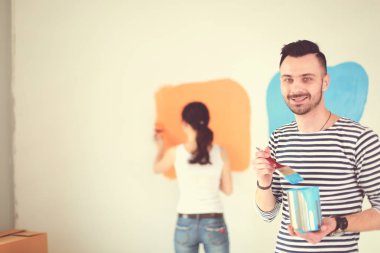 Yeni evin içini boyayan mutlu, genç bir çiftin portresi. Genç çift