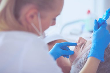 Kaşlar için kalıcı makyaj. Güzellik salonunda kalın kaşlı güzel bir kadın.