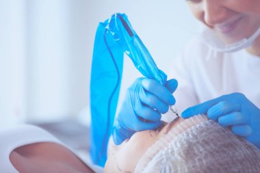 Kaşlar için kalıcı makyaj. Güzellik salonunda kalın kaşlı güzel bir kadın..