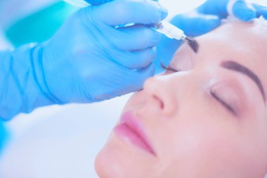 Kaşlar için kalıcı makyaj. Güzellik salonunda kalın kaşlı güzel bir kadın..