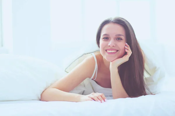 Pretty woman lying down on her bed at home.