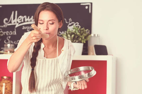 Lachende jonge vrouw met groenten in de keuken. Glimlachende jonge vrouw — Stockfoto