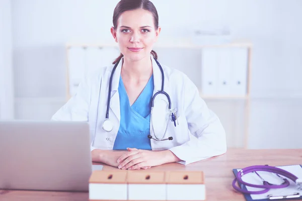 Schöne junge lächelnde Ärztin, die am Schreibtisch sitzt und schreibt. Ärztin — Stockfoto