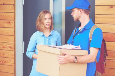 Mavi üniformalı gülümseyen kurye servis konseptine paket kutusu teslim eden teslimatçı. Mavi üniformalı gülümseyen teslimatçı.