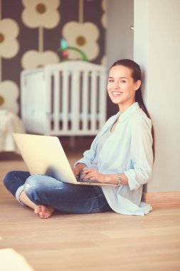 Çocuk karyolası dizüstü bilgisayar ile yakın katta oturan bir genç bayan. Genç anne