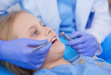 Küçük kız dişçi ofisinde oturuyor.