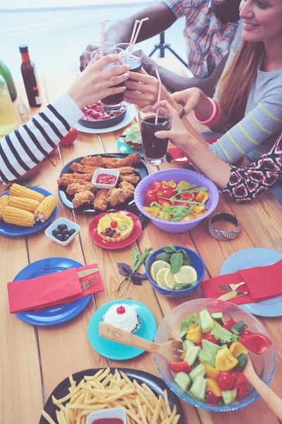 Vista superior do grupo de pessoas que jantam juntas enquanto estão sentadas à mesa de madeira. Comida na mesa. As pessoas comem fast food. — Fotografia de Stock