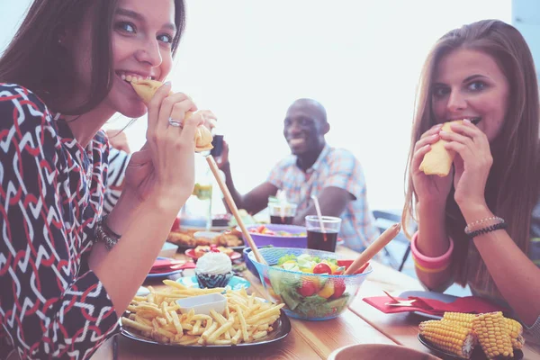 Vista superior do grupo de pessoas que jantam juntas enquanto estão sentadas à mesa de madeira. Comida na mesa. As pessoas comem fast food. — Fotografia de Stock