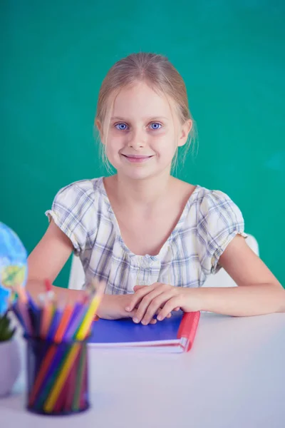 Meisje studeren aan de balie, zittend op het Bureau. — Stockfoto