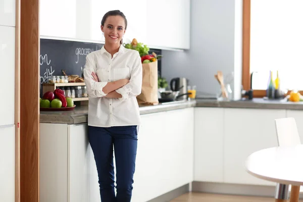 Retrato de mujer joven de pie con los brazos cruzados sobre el fondo de la cocina. Mujer en la cocina . —  Fotos de Stock