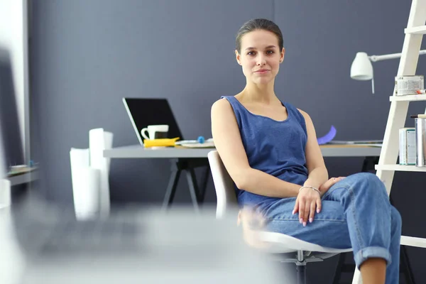 Giovane donna seduta alla scrivania con strumenti, piano e laptop. — Foto Stock