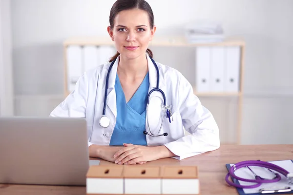 Krásná mladá usmívající se lékařka sedí u stolu a psaní. ženský lékař — Stock fotografie
