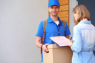 Mavi üniformalı gülümseyen kurye servis konseptine paket kutusu teslim eden teslimatçı. Mavi üniformalı gülümseyen teslimatçı.