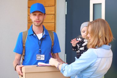 Mavi üniformalı gülümseyen kurye servis konseptine paket kutusu teslim eden teslimatçı. Mavi üniformalı gülümseyen teslimatçı.