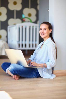Çocuk karyolası dizüstü bilgisayar ile yakın katta oturan bir genç bayan. Genç anne