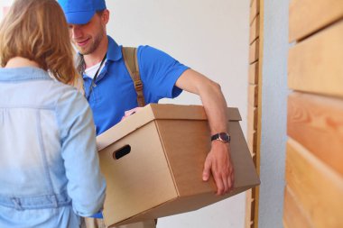 Mavi üniformalı gülümseyen kurye servis konseptine paket kutusu teslim eden teslimatçı. Mavi üniformalı gülümseyen teslimatçı.