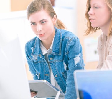 Masanın yanında duran iki genç kadın enstrüman, plan ve dizüstü bilgisayarla.