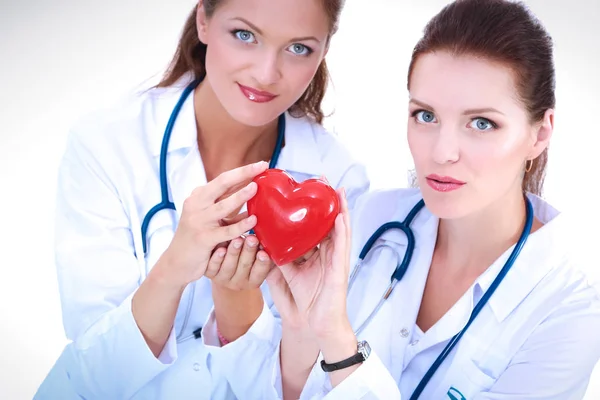 Dos doctora sosteniendo un corazón rojo, aislada sobre fondo blanco — Foto de Stock