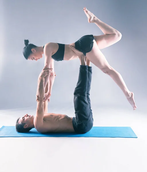 Pasangan muda berlatih akroyoga di atas tikar di studio bersama-sama. Acroyoga. Beberapa yoga. Partner yoga . — Stok Foto