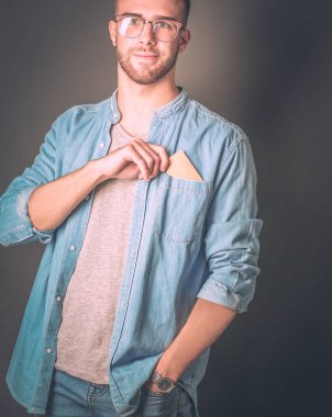 Gri arka planda duran bir kredi kartı tutan genç adam. Genç girişimci..