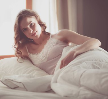 Pencere yakınındaki erken sabah yatakta yatan kadın.