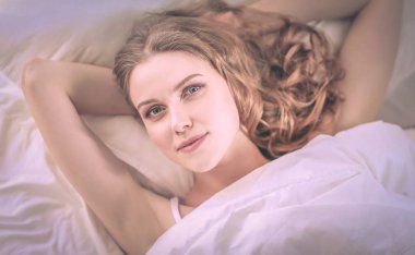 Güzel bir kadın yatağında uzanıyor..
