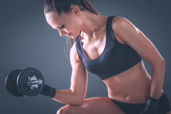 Sportliche Frau pumpt Muskeln mit Kurzhanteln auf — Stockfoto