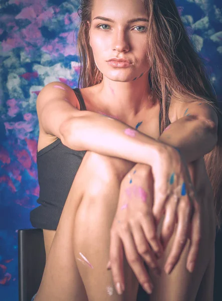 Jovem bela mulher sentada perto da parede da pintura — Fotografia de Stock