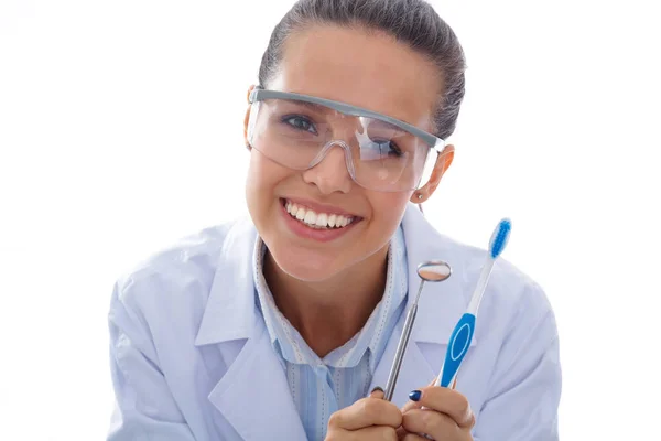 Hermosa doctora dentista sosteniendo y mostrando un cepillo de dientes aislado sobre un fondo blanco. Médico dentista —  Fotos de Stock