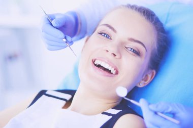 Dişçi muayenehanesinde diş muayenesi yapan ağzı açık genç bir kadın hasta..