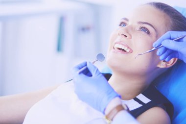 Dişçi muayenehanesinde diş muayenesi yapan ağzı açık genç bir kadın hasta..