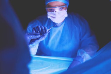 Doktor karanlık bir arka planda ameliyat yapıyor..