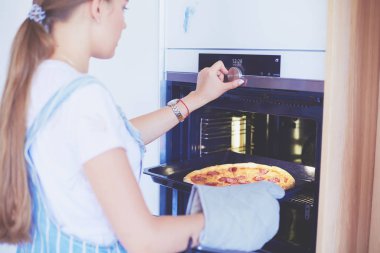 Mutlu genç bayan evde pizza pişiriyor.