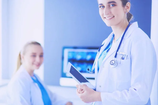 Inyección del médico sosteniendo pastillas y un vaso de agua en la clínica con su colega en el fondo. — Foto de Stock