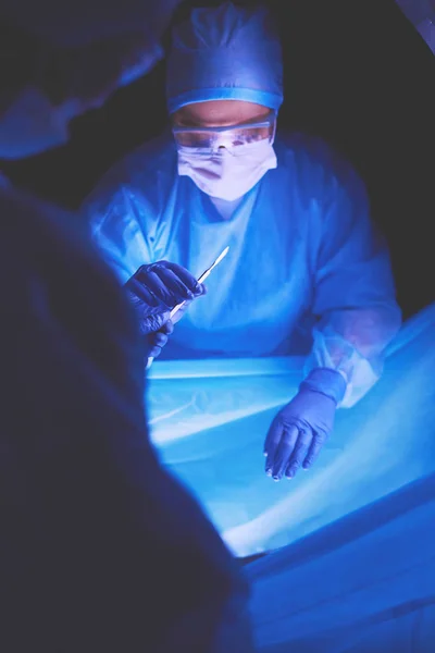 Lékař provádějící operaci v tmavém pozadí. — Stock fotografie